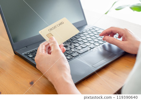 A woman holding a credit card and operating a personal computer 119390640