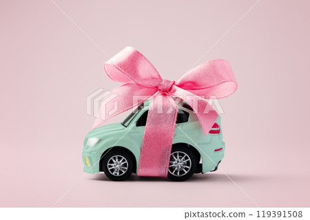 Car gift, car toy with ribbon bow on pink background Car gift, car toy with ribbon bow on pink background 119391508