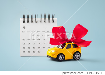 Car gift with red bow and calendar on blue background Car gift with red bow and calendar on blue background 119391511