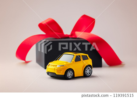 Car toy with black gift box and red bow on beige background Car toy with black gift box and red bow on beige background 119391515