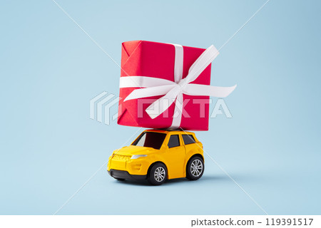Car toy with red christmas gift box on the roof on blue background 119391517