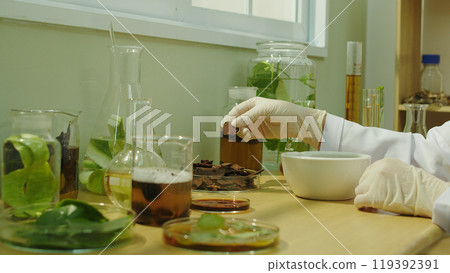 A scientist sit at wooden table by window, conducting an experiment with variety natural shampoo manufacturing ingredients. Template photo for advertising poster design 119392391