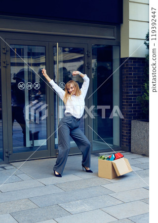 Joy of freedom. Happy young woman in formal wear dancing outside the office, expressing positive emotions after quitting job Joy of freedom. Happy young woman in formal wear dancing outside the office, expressing positive emotions after quitting job 119392447