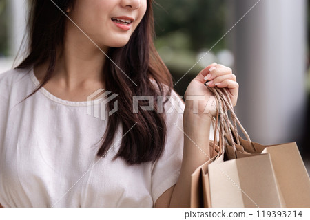 Stylish Woman Enjoying a Shopping Spree at the Mall with Eco-Friendly Paper Bags in Hand 119393214