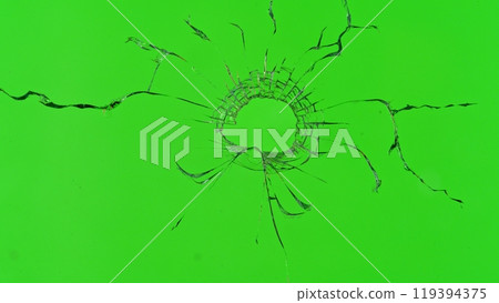 Close-up of gunshot through the glass, shattering against the green background Close-up of gunshot through the glass, shattering against the green background 119394375