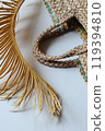 Fragment of a straw bag in natural colors with palm branches. 119394810