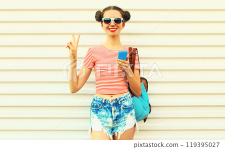 Portrait of happy smiling young woman with smartphone wearing a backpack on white background Portrait of happy smiling young woman with smartphone wearing a backpack on white background 119395027