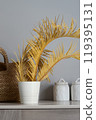 The composition with a straw bag and dry palm branches. Natural materials. Minimalist kitchen utensils. Oceanside lifestyle. Mediterranean style. 119395131