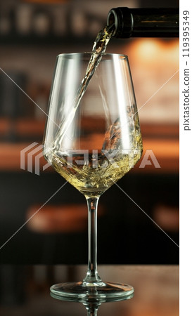 Pouring white wine from bottle. 119395349