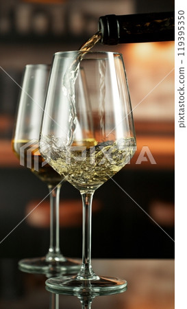 Pouring white wine from bottle. Pouring white wine from bottle. 119395350