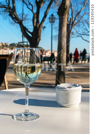 A glass of white wine and an ashtray on a white table of a cafe in the park, drinks on the table in a restaurant 119395410