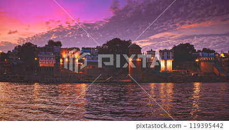 Varanasi, India. Many Boats Moored On Ganga River Near Ghats. Camera Moving Along Riverbank Embankment. General View On Lassi Ghat, Tulsi Ghat and Bhadaini Ghat. Purple Sunset Sky At Evening . Evening Varanasi, India. Many Boats Moored On Ganga River Near Ghats. Camera Moving Along Riverbank Embankment. General View On Lassi Ghat, Tulsi Ghat and Bhadaini Ghat. Purple Sunset Sky At Evening . Evening 119395442
