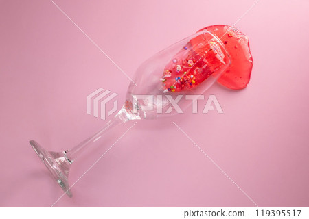 Glass with spilled liquid on pink background Glass with spilled liquid on pink background 119395517