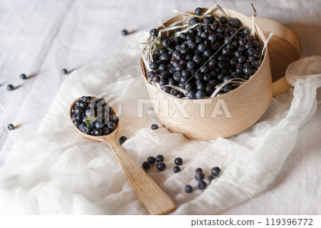 Blueberries. Rustic still life. Freshly harvested blackberries in a wooden bowl on a white cloth with scattered berries. Blueberries. Rustic still life. Freshly harvested blackberries in a wooden bowl on a white cloth with scattered berries. 119396772