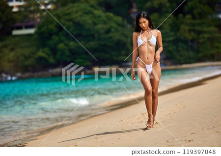 Beautiful asian girl in white bikini posing at the tropical beach Beautiful asian girl in white bikini posing at the tropical beach 119397048