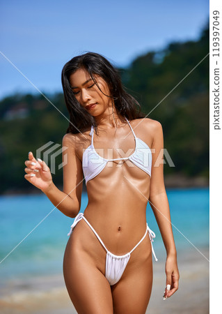 Beautiful asian girl in white bikini posing at the tropical beach. Close-up 119397049