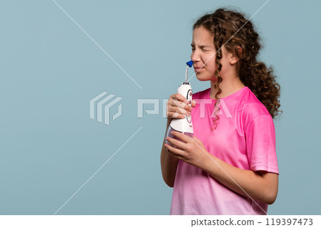 Young girl grimacing while using an oral irrigator Young girl grimacing while using an oral irrigator 119397473