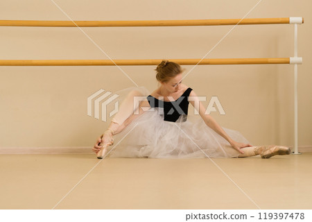 Ballet dancer performs a stretch in a dance studio Ballet dancer performs a stretch in a dance studio 119397478