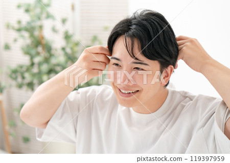 一個男人正在整理頭髮，微笑著 119397959