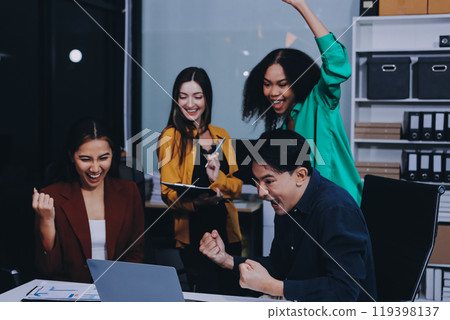 Young corporate employees sitting in office looking at laptop screen reading good news excited happy team diverse people celebrating victory win command success excellent result professional teamwork 119398137
