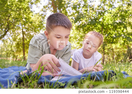 Children reading together in a sunny park summertime learning and friendship 119398444
