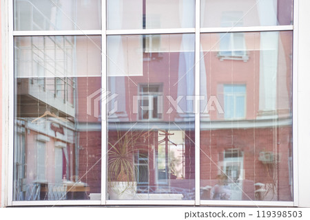 Reflection of urban architecture in large glass window with indoor plant 119398503