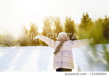 Happy beautiful child portrait. Excited kid playing in winter mountains forest. Funny little girl throwing snow into air, having fun. Snowy evergreen trees around ski resort. Christmas holiday vibes 119398904