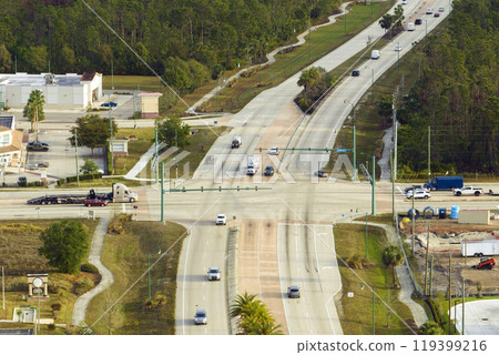 Top view of wide road with moving cars at intersection with traffic lights. City transportation in the USA. American town traffic from above Top view of wide road with moving cars at intersection with traffic lights. City transportation in the USA. American town traffic from above 119399216
