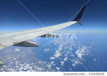 View through airplane window of commercial jet plane wing flying high in the sky. Air travelling concept View through airplane window of commercial jet plane wing flying high in the sky. Air travelling concept 119399248