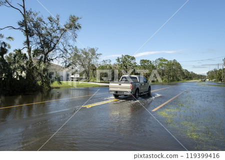 Hurricane flooded street with moving cars in surrounded with water Florida residential area. Consequences of natural disaster 119399416