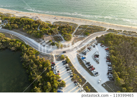 Parking lot for tourists cars in front of ocean beach with soft white sand in Florida. Popular vacation spot at sunset Parking lot for tourists cars in front of ocean beach with soft white sand in Florida. Popular vacation spot at sunset 119399465