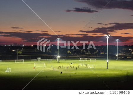 People playing soccer game on illuminated public stadium at sunset. Active way of life concept People playing soccer game on illuminated public stadium at sunset. Active way of life concept 119399466