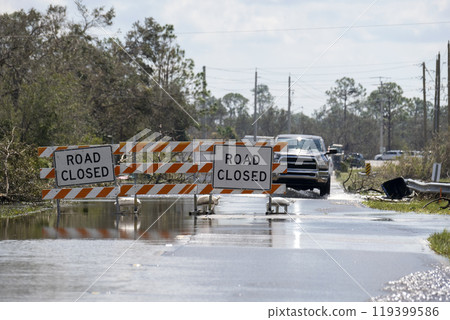 Flooded street in Florida after hurricane rainfall with road closed signs blocking driving of cars. Safety of transportation during natural disaster concept Flooded street in Florida after hurricane rainfall with road closed signs blocking driving of cars. Safety of transportation during natural disaster concept 119399586