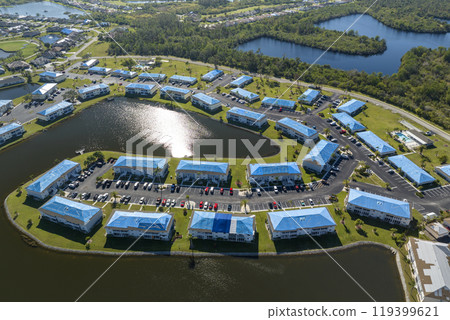 Hurricane damaged apartment buildings rooftops covered with protective plastic tarp against rain water leaking until replacement of asphalt shingles. Aftermath of natural disaster 119399621