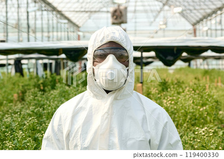 Front view portrait of man wearing protective suit in greenhouse and looking at camera Front view portrait of man wearing protective suit in greenhouse and looking at camera 119400330