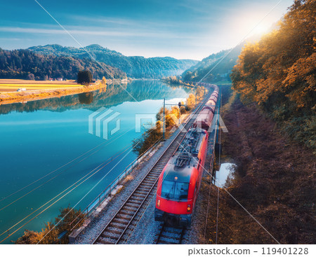 Aerial view of red high speed train moving near lake in mountains 119401228