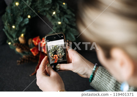 Woman photographing black cat with Christmas wreath and lights for social media content. Festive holiday decorations in cozy home setting. Woman photographing black cat with Christmas wreath and lights for social media content. Festive holiday decorations in cozy home setting. 119401371