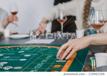 Hands playing at a wine-themed casino game, with glasses of rose in the background, blending gambling and wine tasting Hands playing at a wine-themed casino game, with glasses of rose in the background, blending gambling and wine tasting 119401389