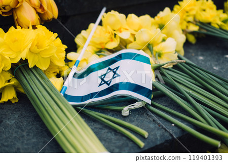 Israeli flag and yellow daffodils on stone steps, symbolizing Holocaust remembrance and national mourning 119401393