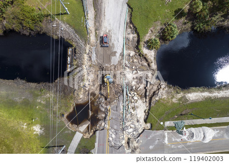 Construction equipment at roadworks site. Reconstruction of damaged road bridge destroyed by river after flood water washed away asphalt. Rebuilding of ruined transportation infrastructure 119402003