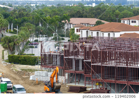 Construction site with hardhat workers assembling metal frame walls. Aerial view of large development area of commercial structure. Real estate market in the USA Construction site with hardhat workers assembling metal frame walls. Aerial view of large development area of commercial structure. Real estate market in the USA 119402006