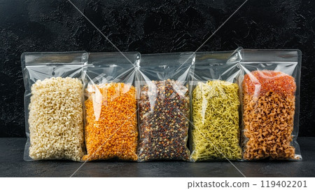 Assorted Dry Pasta and Grains in Transparent Bags Against Dark Background 119402201