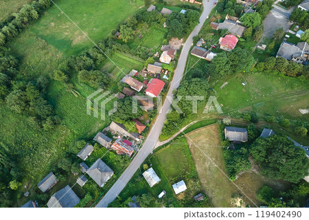 Aerial landscape view of village houses and distant green cultivated agricultural fields with growing crops on bright summer day Aerial landscape view of village houses and distant green cultivated agricultural fields with growing crops on bright summer day 119402490