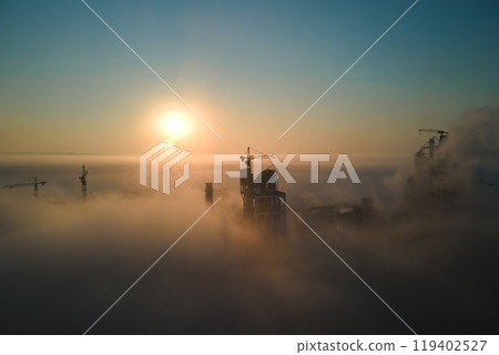 Aerial view of cement factory with high concrete plant structure and tower crane at industrial production site on foggy morning. Manufacture and global industry concept. 119402527