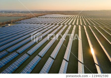 Aerial view of large sustainable electrical power plant with rows of solar photovoltaic panels for producing clean electric energy in evening. Concept of renewable electricity with zero emission Aerial view of large sustainable electrical power plant with rows of solar photovoltaic panels for producing clean electric energy in evening. Concept of renewable electricity with zero emission 119402590