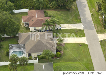 Aerial view of small town America suburban landscape with private homes between green palm trees in Florida quiet residential area Aerial view of small town America suburban landscape with private homes between green palm trees in Florida quiet residential area 119402623