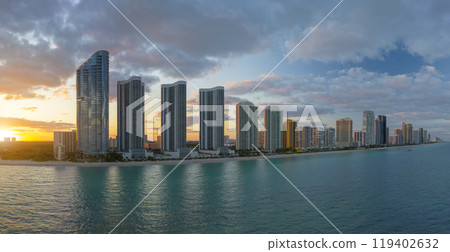 Aerial view of Sunny Isles Beach city with luxurious highrise hotels and condos on Atlantic ocean shore at sunset. American tourism infrastructure in southern Florida 119402632