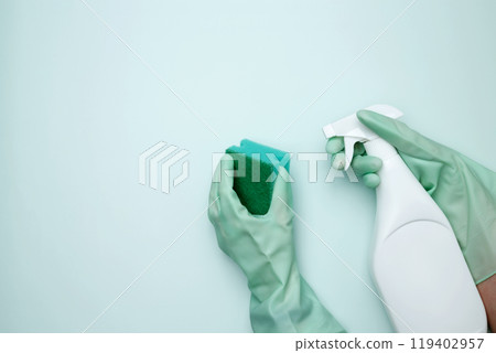 Womans hand in rubber glove holds green dishwashing sponge and cleaning product. House cleaning. Copy space Womans hand in rubber glove holds green dishwashing sponge and cleaning product. House cleaning. Copy space 119402957