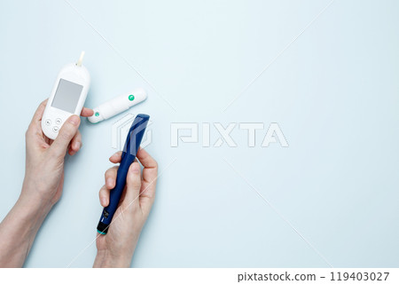 Female hands holding glucometer for measuring blood glucose levels,  lancet. Concept of worldwide diabetes awareness 119403027