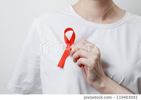 Woman holding red AIDS awareness ribbon. World AIDS Day 119403091